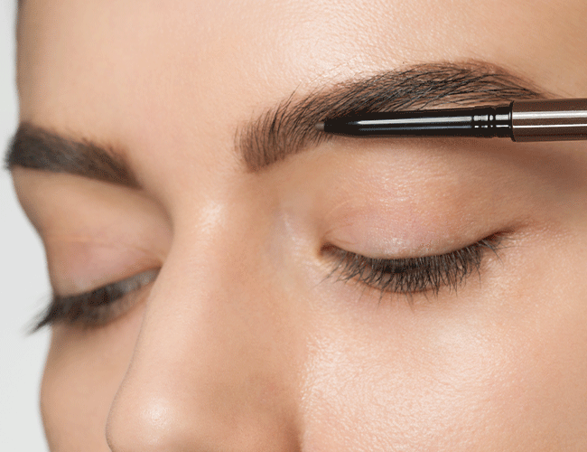 Mit einem Augenbrauen-Stift werden die Augenbrauen nachgezeichnet und gekämmt