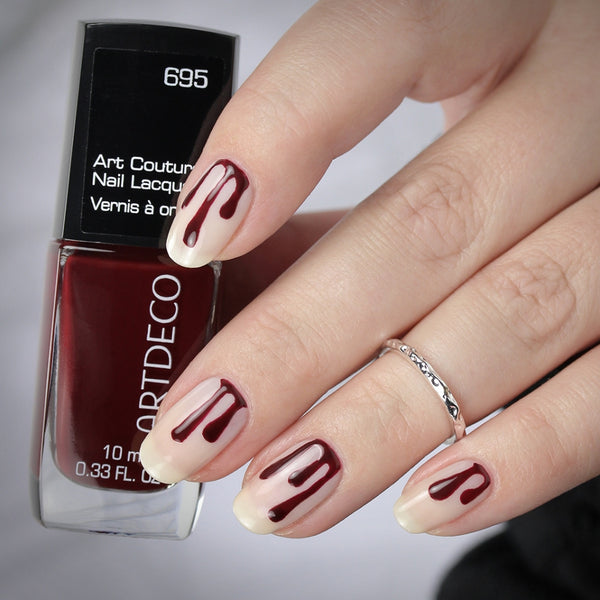 Hand mit fertigem Halloween Nagel Design hält den Art Couture Nail Lacquer in der Farbe 695.