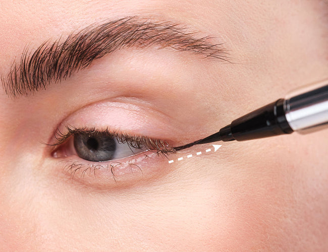 Ein weißer Pfeil zeigt wie man einen klassischen Eyeliner zeichnet.