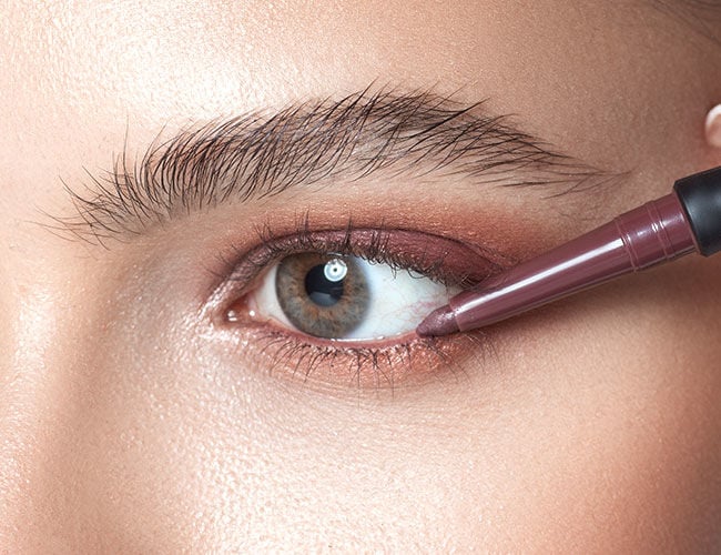 Mit einem Eyeliner in einer beerigen Nuance wird die Wasserlinie betont 