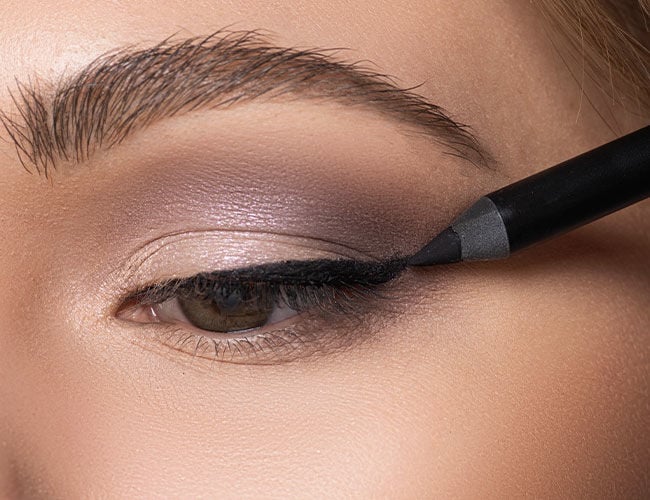 Mit einem schwarzen Khol Eyeliner wird ein Lidstrich gezogen