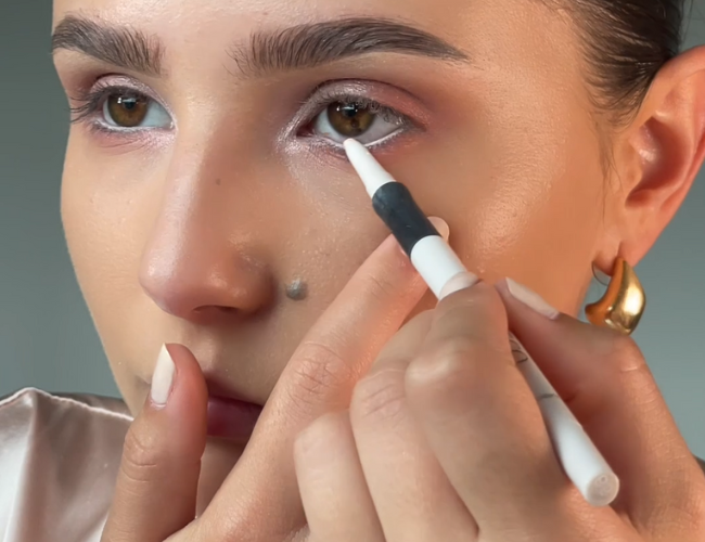 Ein weißer Kajal wird auf die untere Wasserlinie aufgetragen.