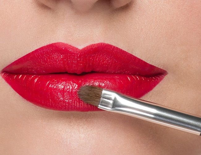 Roter Lippenstift wird mit einem Lippenpinsel aufgetragen