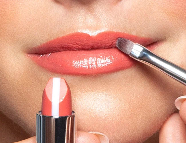 Close.up auf Lippen des Models auf welche eine sommerliche Lippenstiftfarbe mit einem Lippen-Pinsel aufgetragen wird 