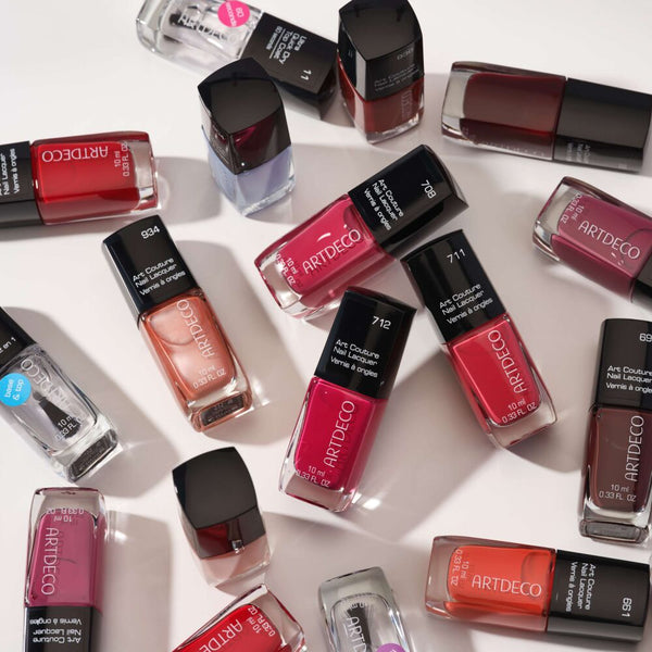 Mehrere ARTDECO Nagellacke in verschiedenen Farben liegen auf hellem Untergrund und zeigen eine vielfältige Auswahl an Rot-, Pink-, Orange-, Nude- und Lilatönen