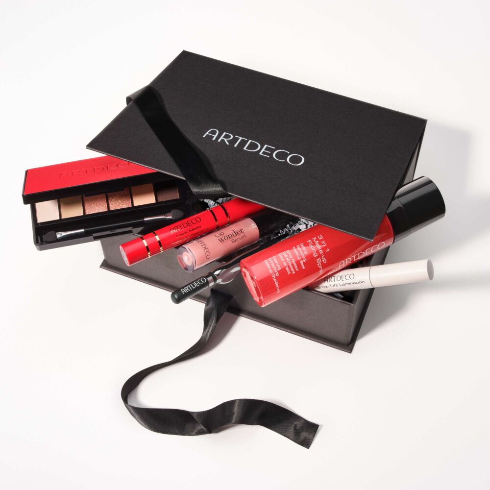 ARTDECO Online Exclusive Adventskalender in schwarzer Geschenkbox mit Satinband und ausgewählten Make-up-Produkten, darunter Iconic Eyeshadow Palette, Lash Hero Tubing Mascara im roten Design, Lip Wonder Serum und Brow Lift Lamination.